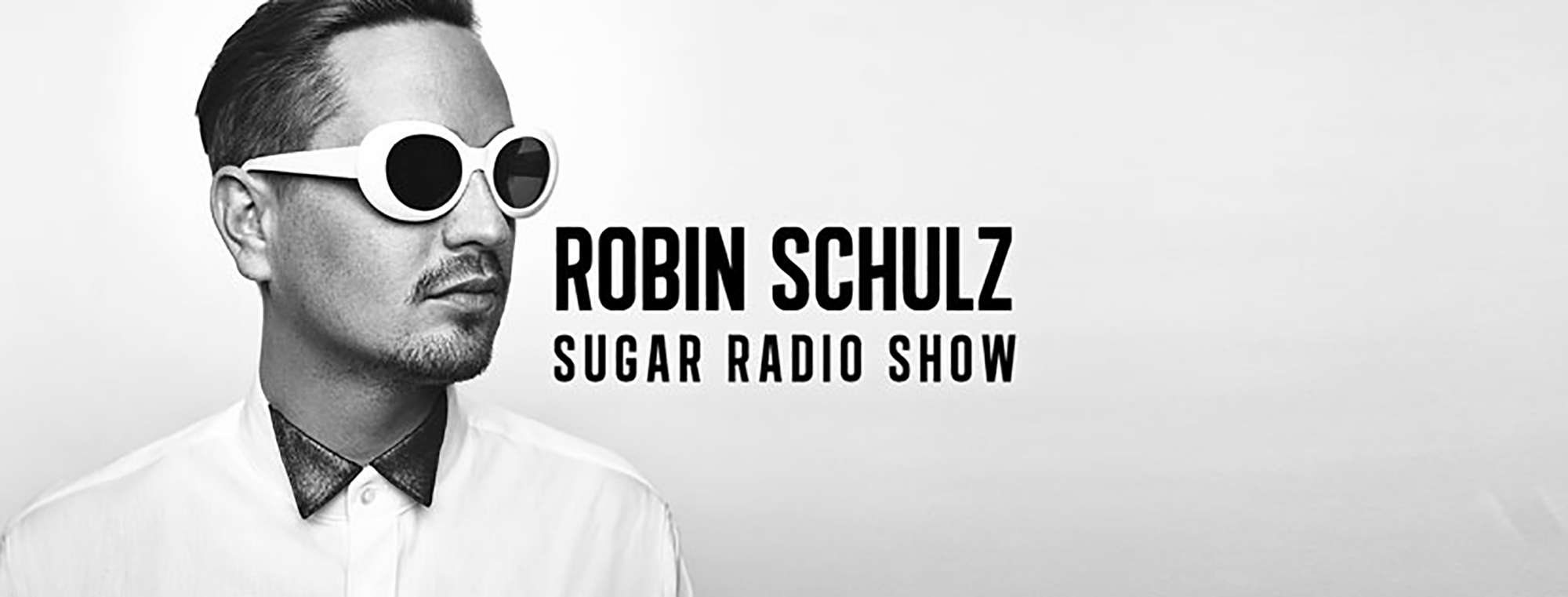 A black and white image of chart hit artist Robin Schulz. He is wearing a shirt and large, white sunglasses. He looks to the right with a neutral expression at the words "Robin Schulz Sugar Radio Show"